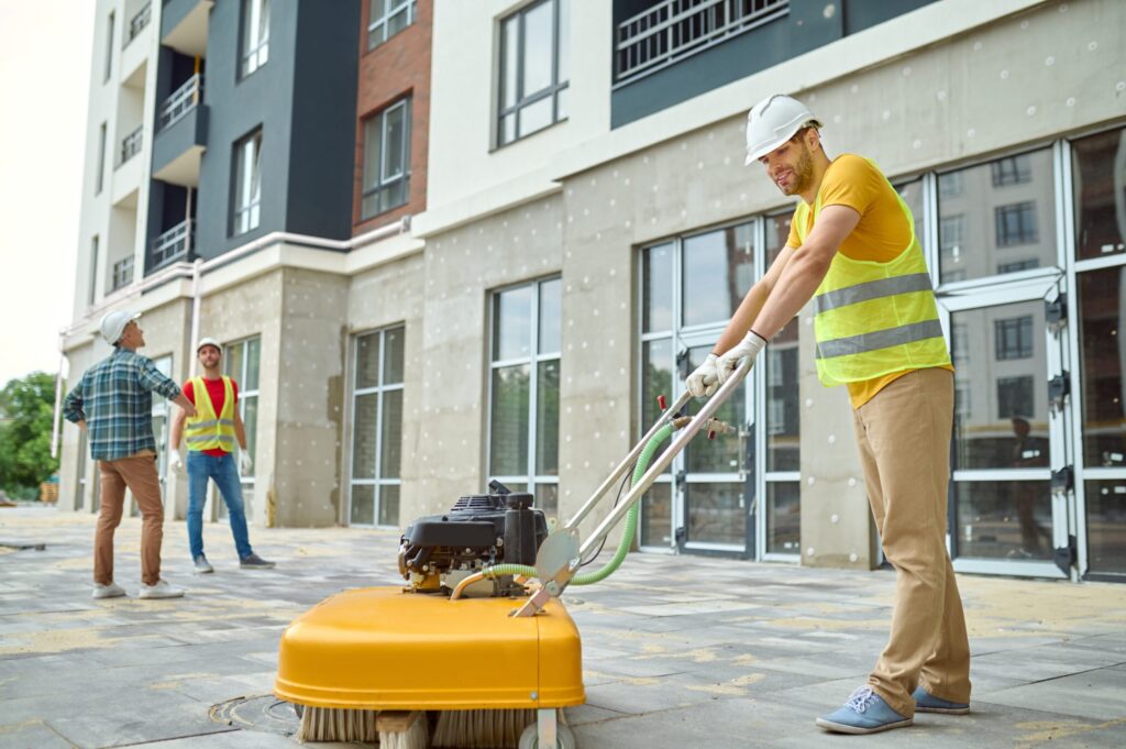 Worker using outdoor cleaning machine on building site