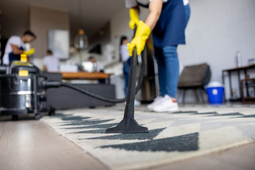 Worker using vacuum equipment to clean a carpet