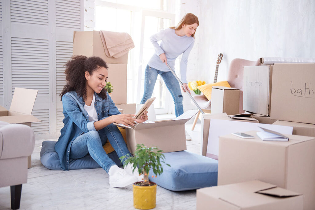Two women unpacking and cleaning among moving boxes