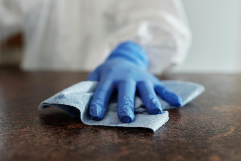 Gloved hand cleaning a surface with a cloth