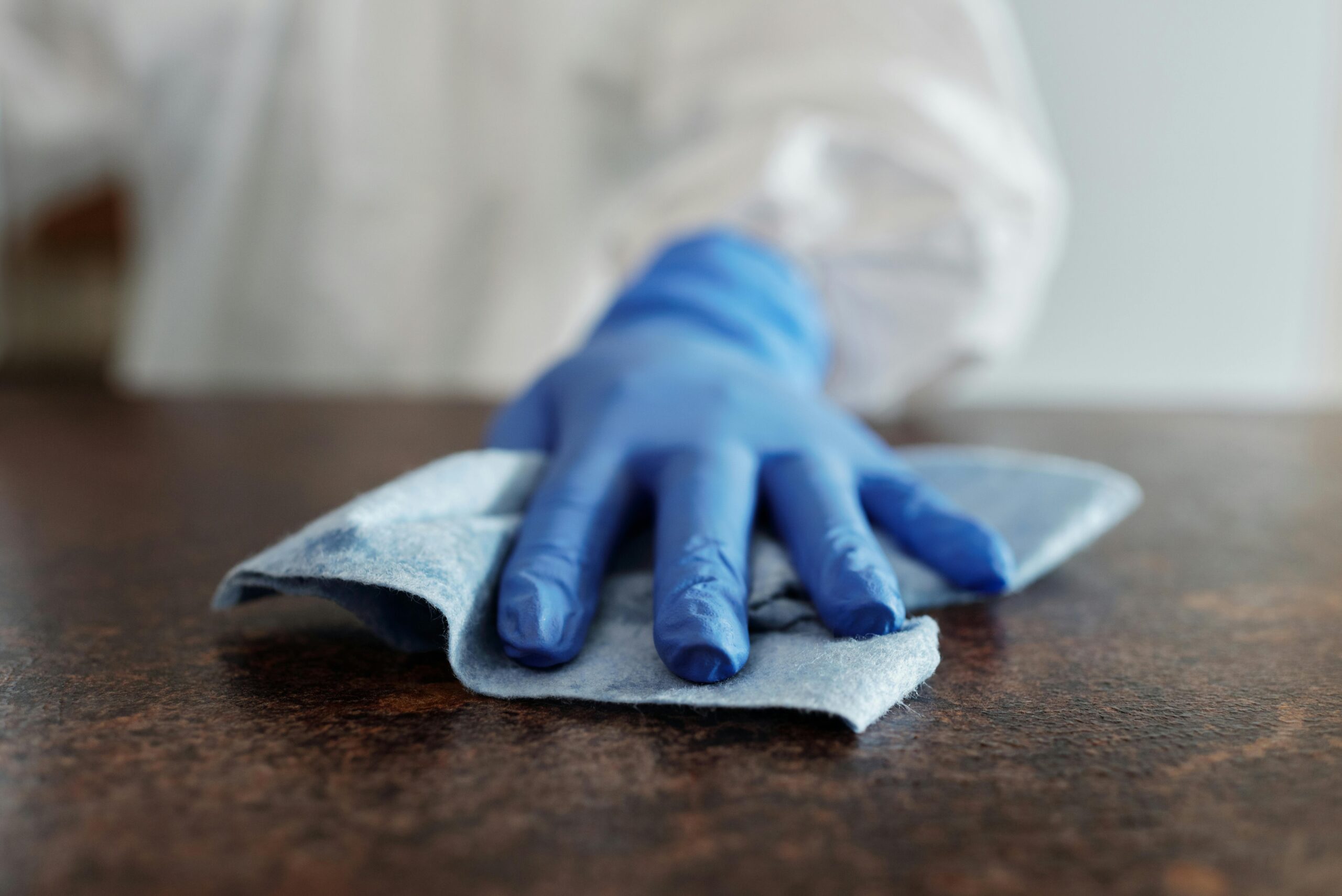 Gloved hand cleaning a surface with a cloth